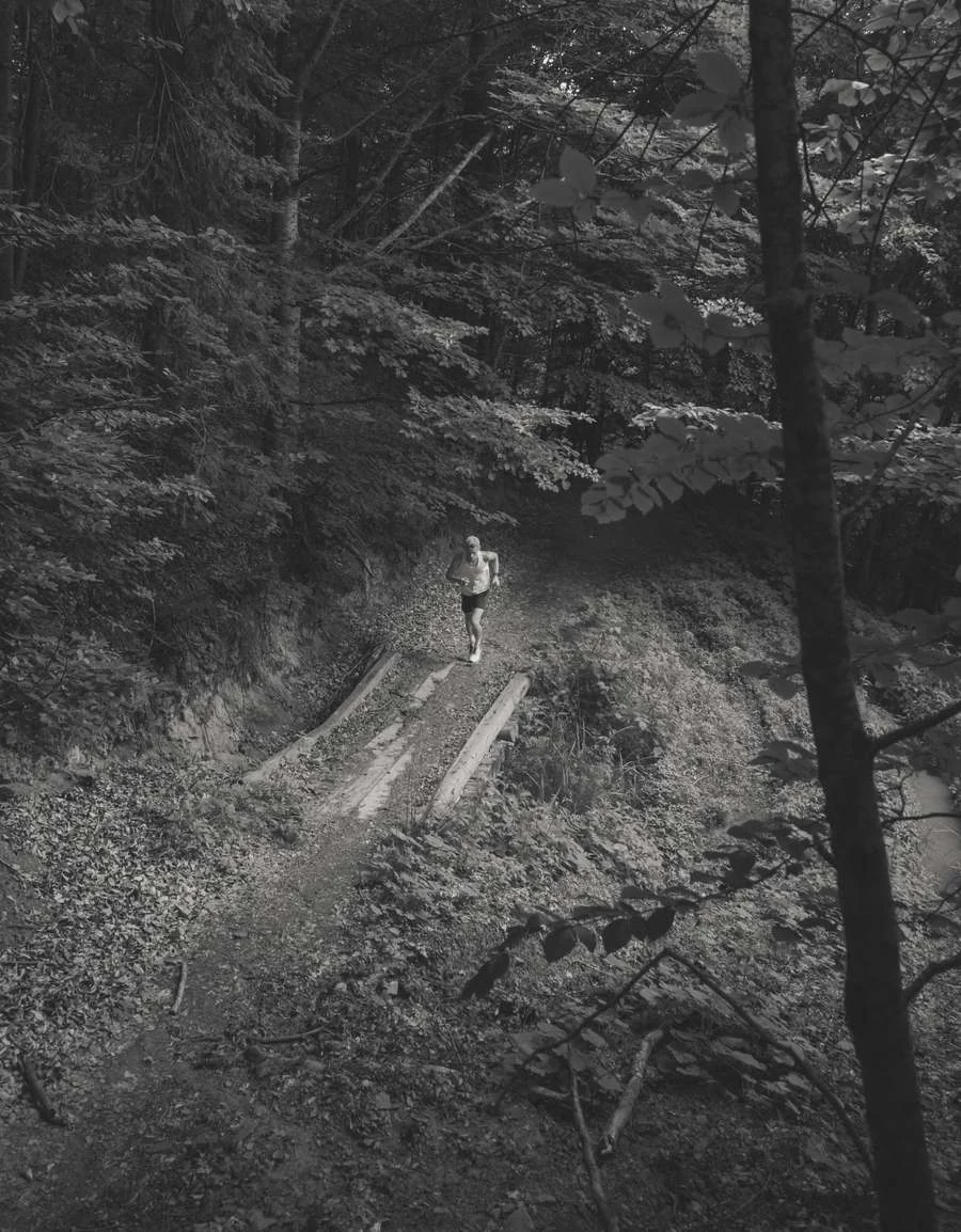 Corredor subiendo por un sendero en el bosque, visto desde arriba