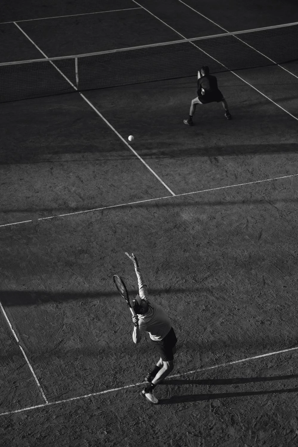 Partido de tenis en cancha de polvo de ladrillo, visto desde arriba